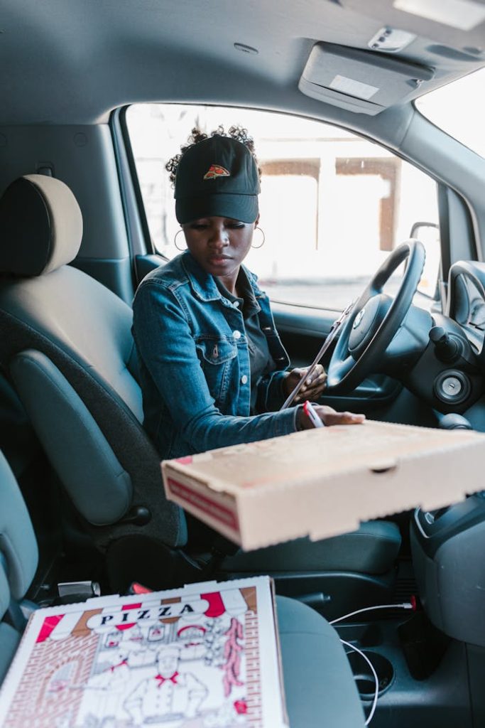 Woman in a car preparing to deliver pizza with a clipboard. Perfect for delivery and career themes.