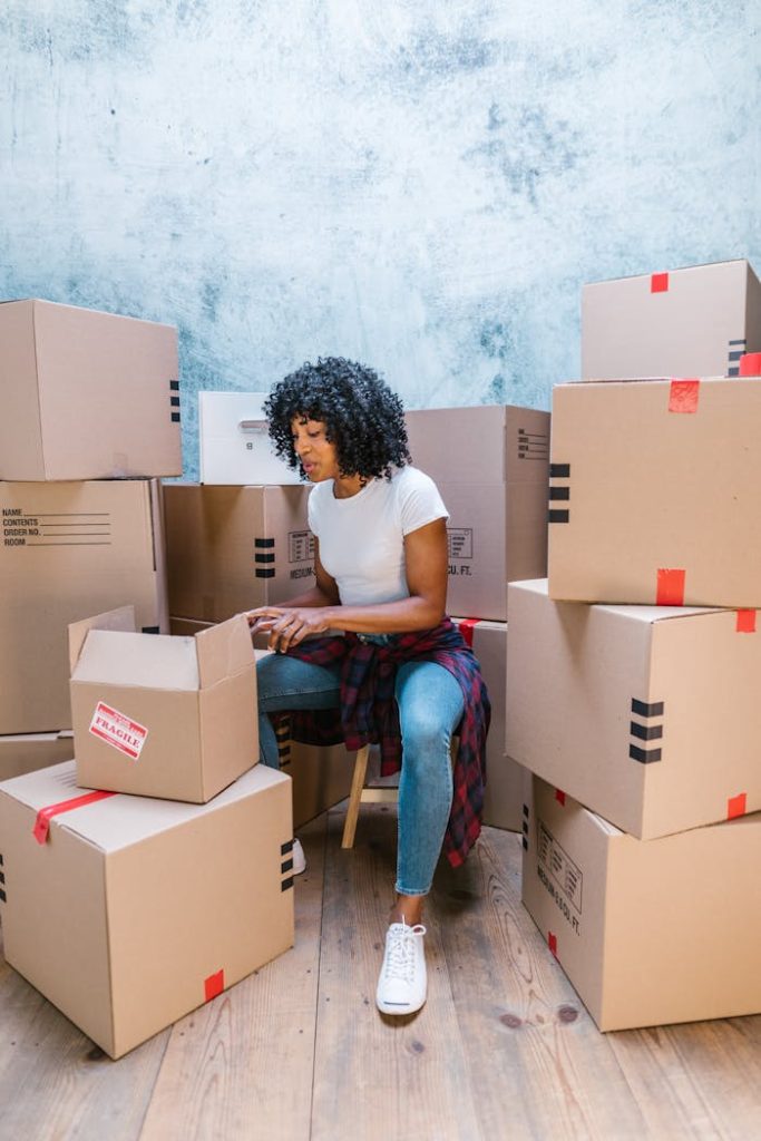 A woman organizing cardboard boxes in a blue-toned room, preparing for a move.